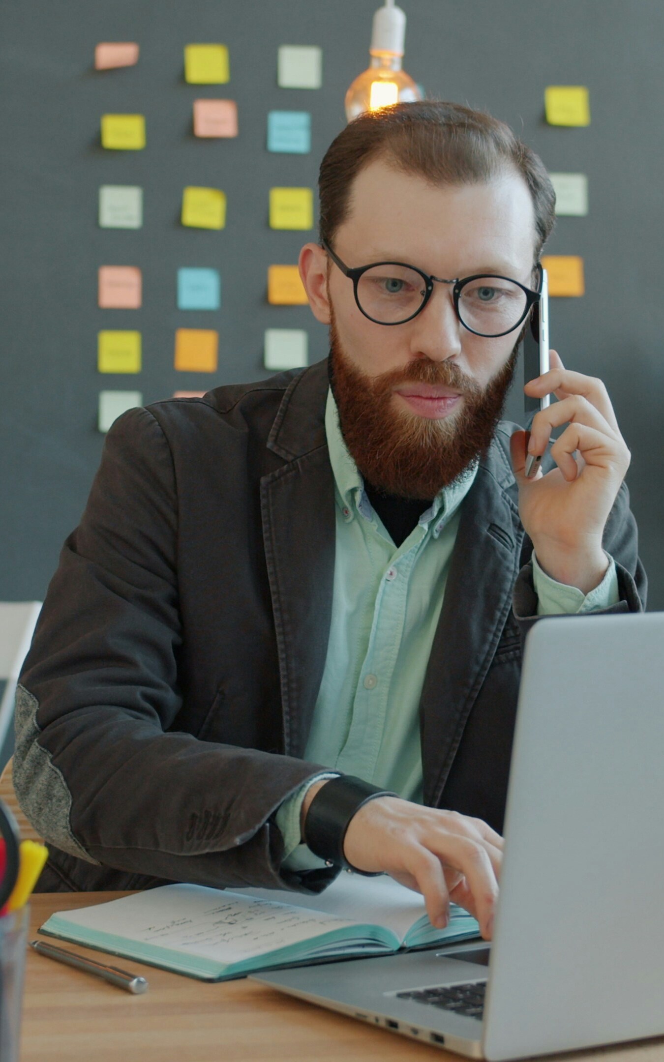 Man talking on a smartphone while using a laptop